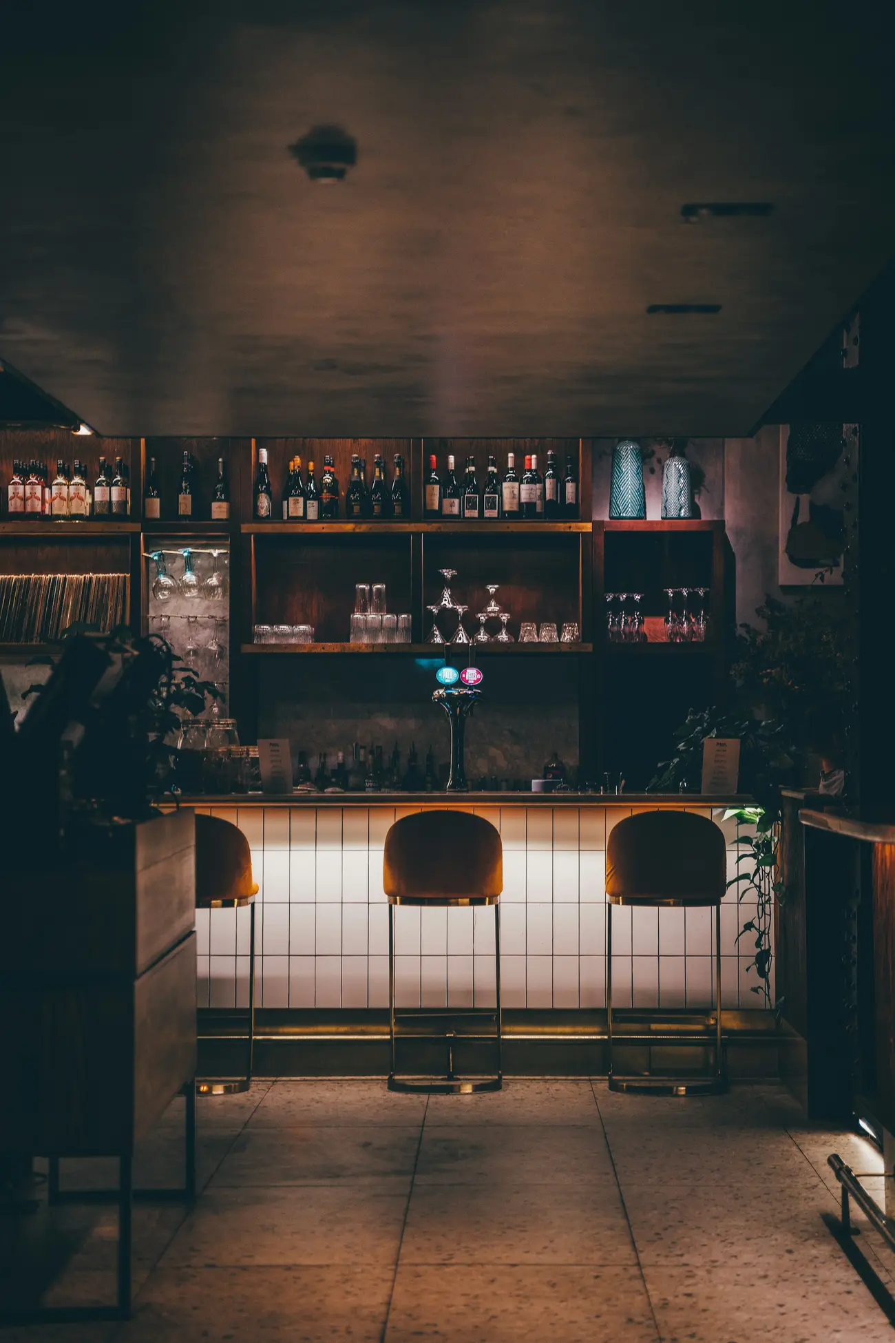 Bar counter with stools and shelves of bottles (illustrative)