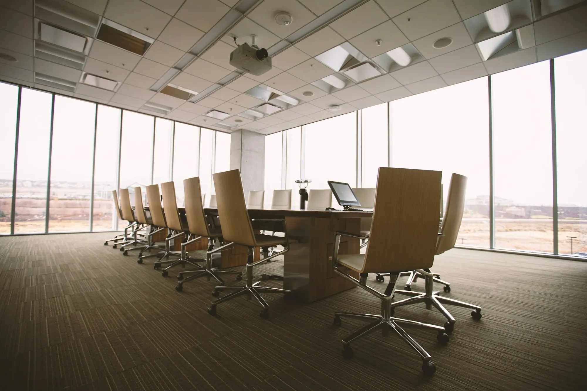 Boardroom table with leather chairs by tall windows (illustrative)